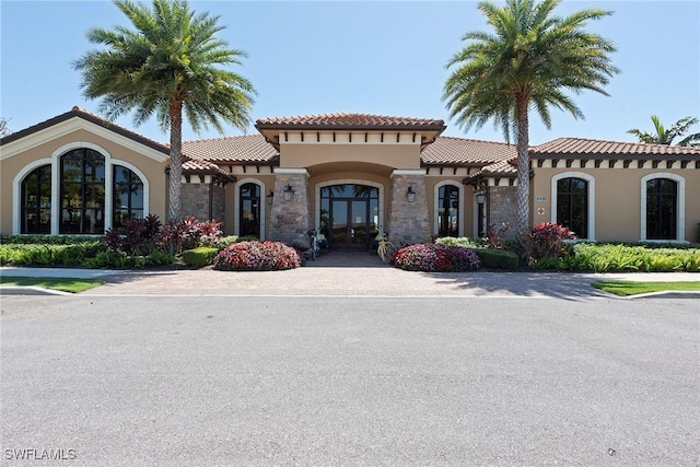 view of front facade featuring stone siding, a tile roof, and stucco siding