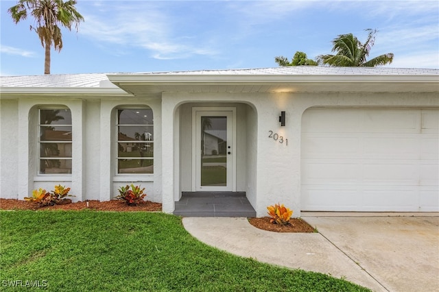 view of exterior entry with a garage and a yard