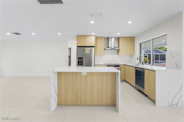 kitchen featuring stainless steel appliances, light stone counters, wall chimney range hood, a center island, and light tile patterned flooring