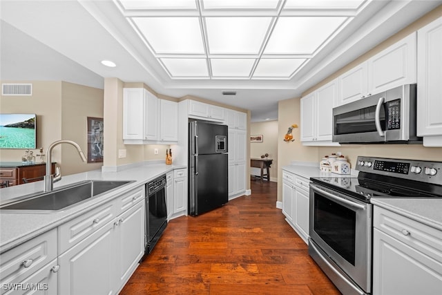 kitchen with dark wood-type flooring, black appliances, white cabinets, and sink