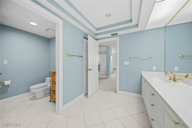 bathroom with tile patterned flooring, vanity, toilet, and a tray ceiling