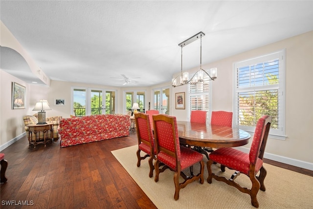 dining area featuring ceiling fan with notable chandelier, dark hardwood / wood-style flooring, and french doors