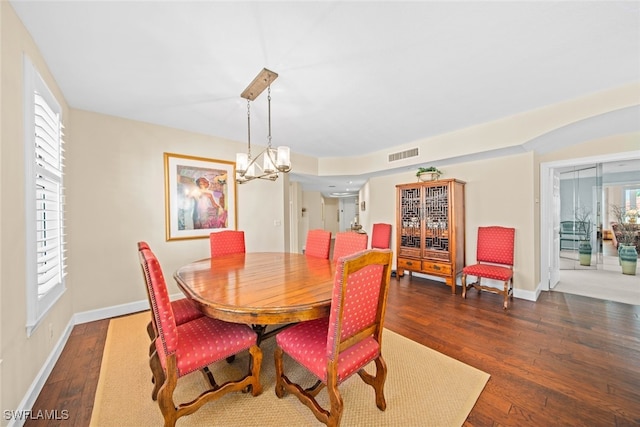 dining area with dark wood-type flooring and a notable chandelier