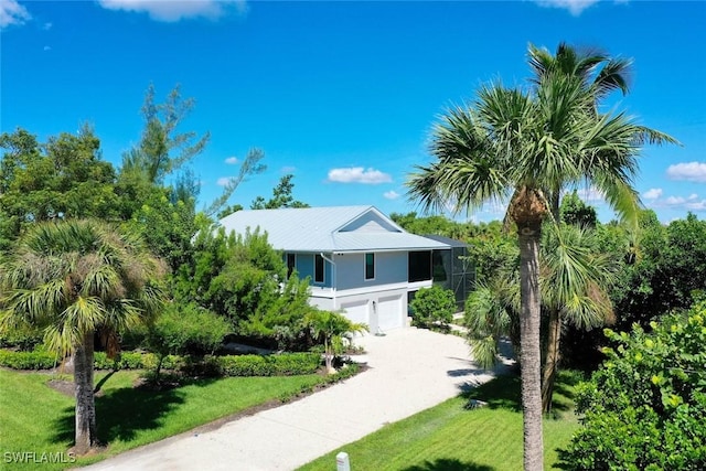 1610 Sabal Sands Rd, Sanibel, FL 33957 - view of front of house with driveway, a garage, stucco siding, a front yard, and metal roof