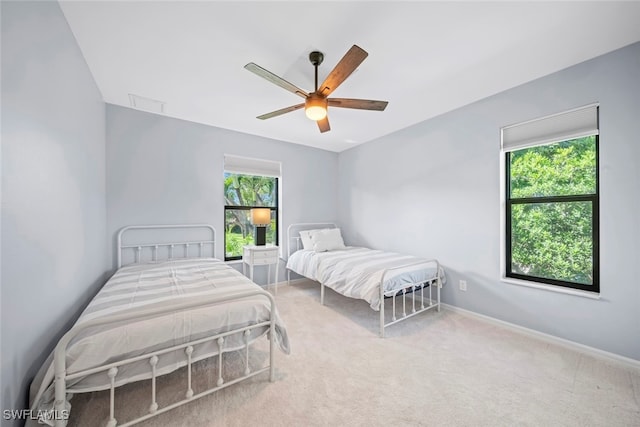 carpeted bedroom featuring multiple windows and ceiling fan