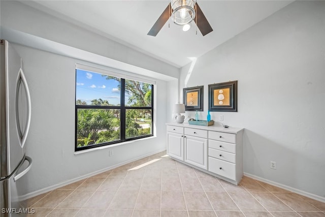 unfurnished bedroom with vaulted ceiling, ceiling fan, light tile patterned flooring, and stainless steel refrigerator