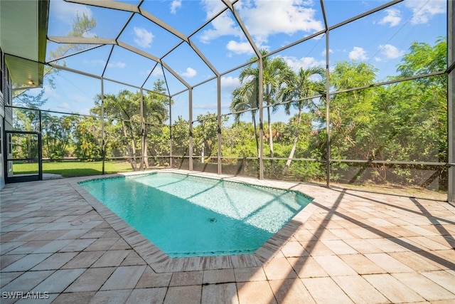 view of pool with glass enclosure and a patio