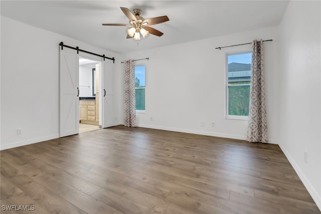 spare room with a barn door, ceiling fan, and hardwood / wood-style floors