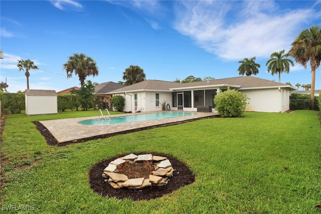 back of property with a fire pit, a fenced in pool, a lawn, and a shed