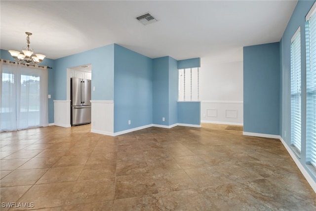 unfurnished room featuring a chandelier