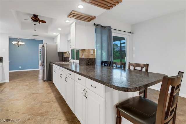 kitchen featuring sink, a breakfast bar area, kitchen peninsula, and white cabinets