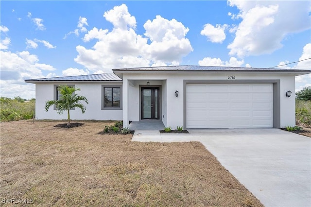 516 Kilarney Ave S, Lehigh Acres, FL 33974 - view of front facade with a garage, driveway, metal roof, and stucco siding