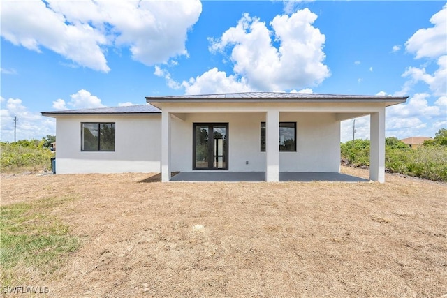 516 Kilarney Ave S, Lehigh Acres, FL 33974 - rear view of house featuring a patio, stucco siding, and metal roof