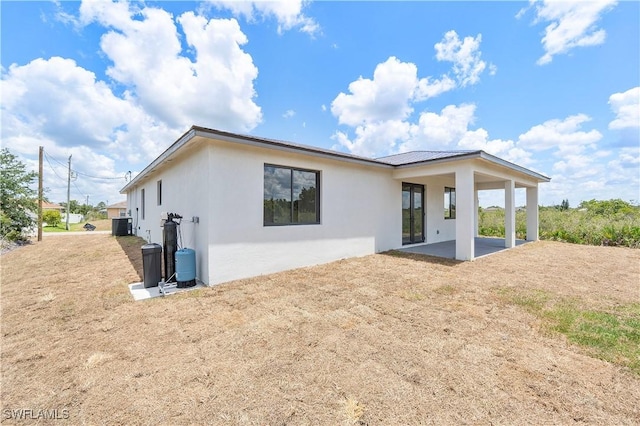 516 Kilarney Ave S, Lehigh Acres, FL 33974 - rear view of property with a patio, central AC, stucco siding, and metal roof
