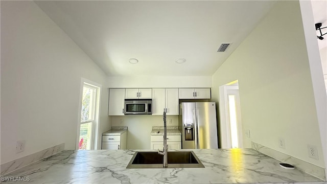 kitchen featuring vaulted ceiling, stainless steel appliances, white cabinetry, and light stone counters