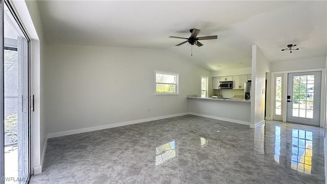 unfurnished living room featuring ceiling fan, a healthy amount of sunlight, and vaulted ceiling