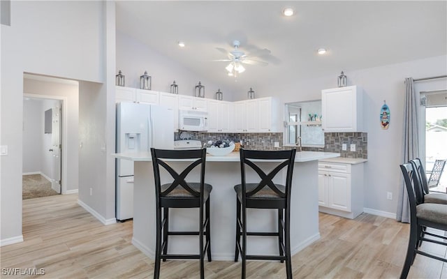 1013 SW 4th Pl, Cape Coral, FL 33991 - kitchen with white appliances, a breakfast bar area, backsplash, white cabinets, and a ceiling fan