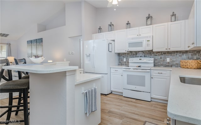 kitchen with light hardwood / wood-style flooring, white appliances, a breakfast bar, and white cabinets