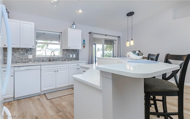 1013 SW 4th Pl, Cape Coral, FL 33991 - kitchen with white dishwasher, a sink, backsplash, a kitchen breakfast bar, and light wood-style flooring