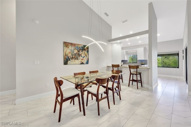 dining area with a towering ceiling, baseboards, and visible vents