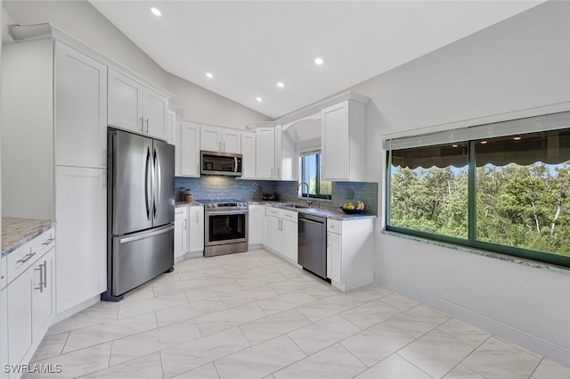 kitchen with stainless steel appliances, white cabinetry, a sink, and light stone counters