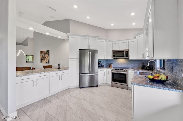 kitchen featuring light stone countertops, sink, stainless steel appliances, and vaulted ceiling