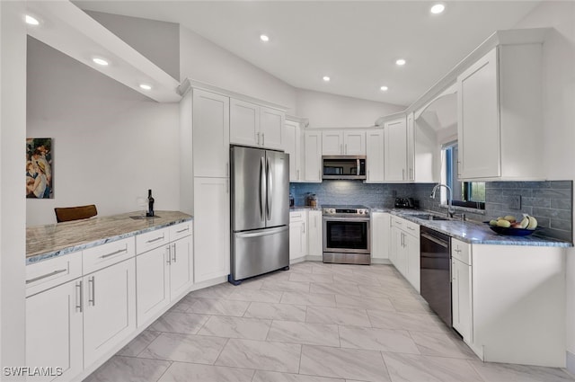 kitchen with light stone countertops, appliances with stainless steel finishes, sink, white cabinets, and lofted ceiling