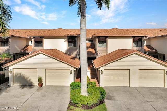 view of front of house with concrete driveway, a tile roof, and stucco siding