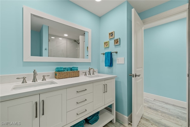 bathroom featuring a sink, a stall shower, wood finished floors, and double vanity
