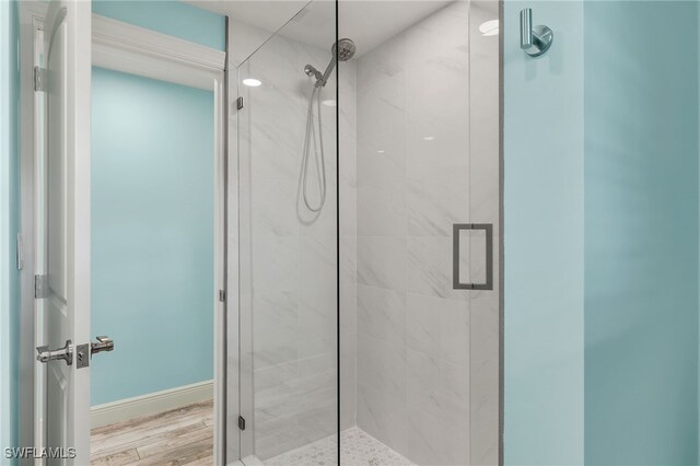 bathroom featuring a shower with shower door and wood-type flooring