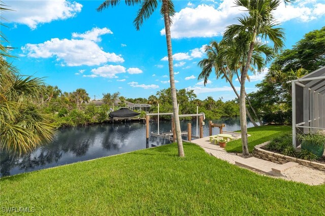 dock area with a lanai, a water view, and a yard