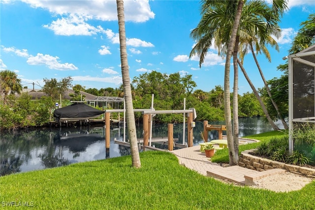 dock area with boat lift, a lawn, and a water view