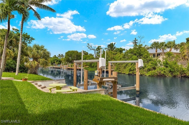 dock area with boat lift, a yard, and a water view