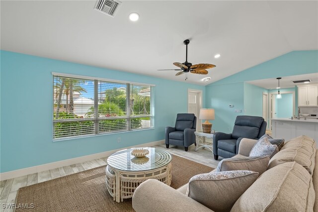 living room with light hardwood / wood-style flooring, ceiling fan, and vaulted ceiling