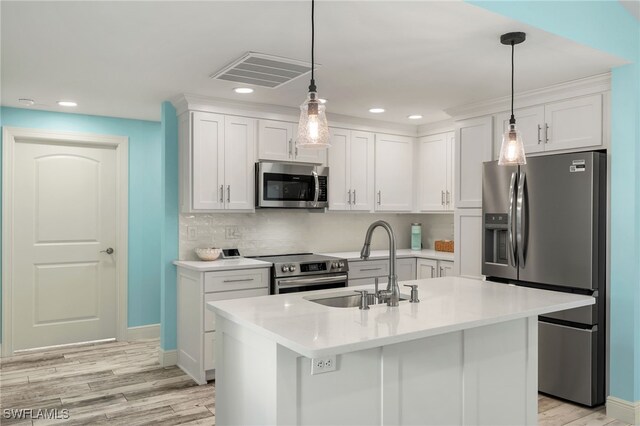 kitchen featuring white cabinets, light hardwood / wood-style flooring, appliances with stainless steel finishes, sink, and a kitchen island with sink