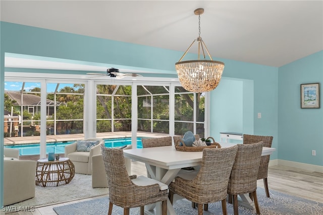 dining room with ceiling fan with notable chandelier, baseboards, and wood finished floors