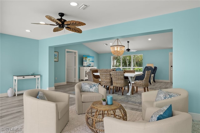 living room with light wood-type flooring, ceiling fan with notable chandelier, and lofted ceiling