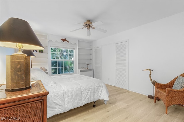 bedroom featuring ceiling fan, two closets, and hardwood / wood-style flooring