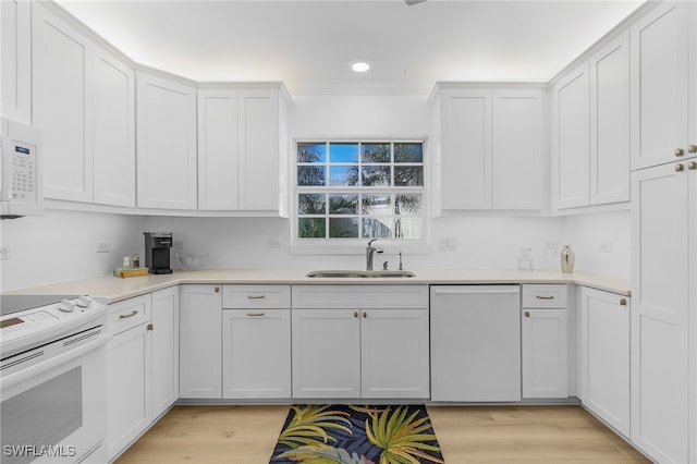 kitchen with sink, white appliances, white cabinetry, and light hardwood / wood-style floors