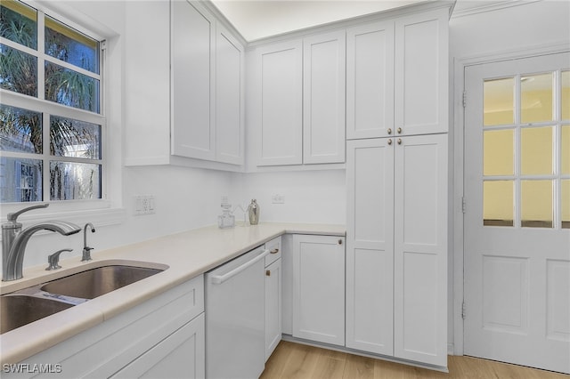 kitchen featuring white dishwasher, sink, and white cabinets