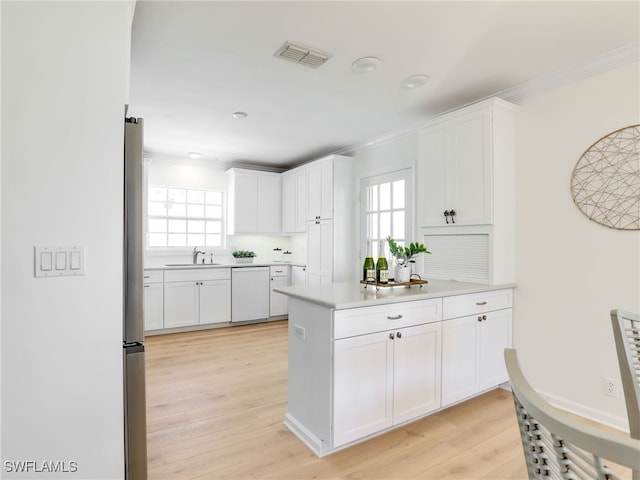 2601 Gulf Shore Blvd N Unit 34, Naples, FL 34103 - kitchen featuring white dishwasher, crown molding, white cabinetry, light countertops, and light wood-style flooring