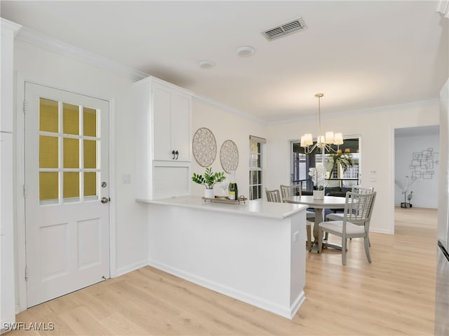 2601 Gulf Shore Blvd N Unit 34, Naples, FL 34103 - kitchen featuring light wood-style flooring, ornamental molding, a chandelier, white cabinets, and a peninsula