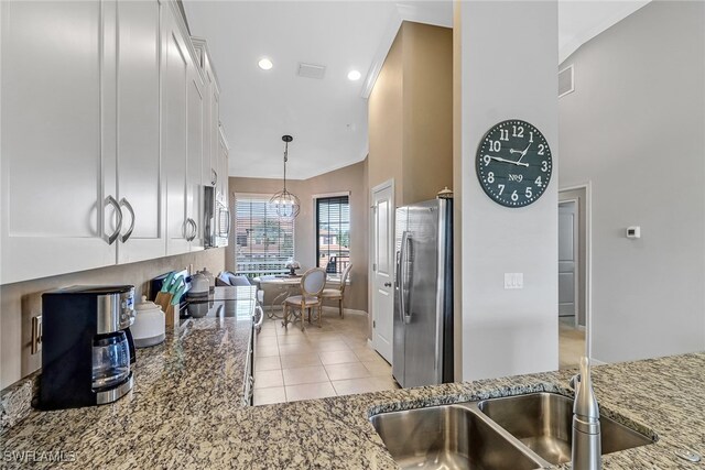 kitchen with light tile patterned flooring, decorative light fixtures, appliances with stainless steel finishes, light stone counters, and white cabinets