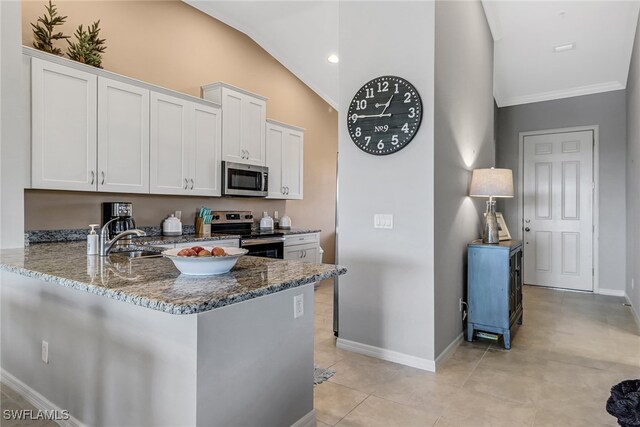 kitchen featuring white cabinets, light tile patterned floors, dark stone countertops, lofted ceiling, and stainless steel appliances