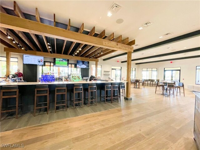 interior space with beam ceiling, a breakfast bar area, and light hardwood / wood-style floors