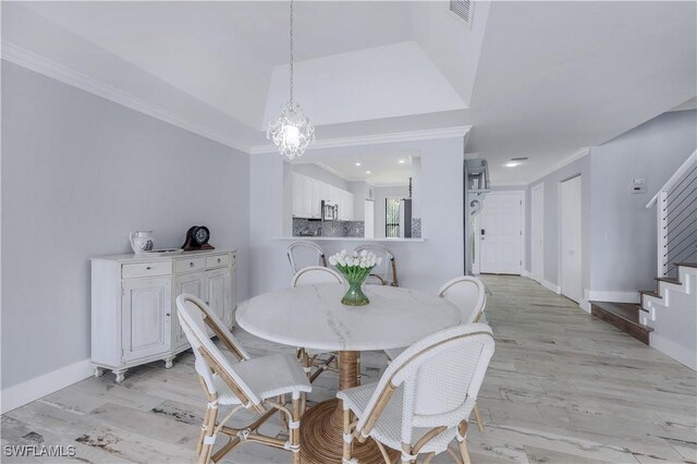 dining area featuring crown molding, light hardwood / wood-style floors, and a notable chandelier