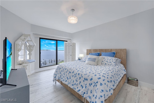 bedroom featuring a water view, light hardwood / wood-style flooring, and access to exterior