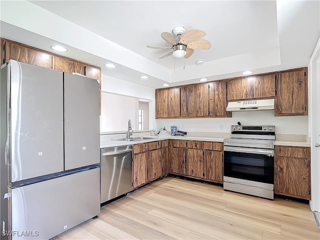 kitchen featuring ceiling fan, light wood-type flooring, a raised ceiling, and stainless steel appliances