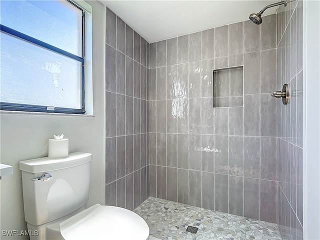 bathroom featuring tiled shower, plenty of natural light, and toilet