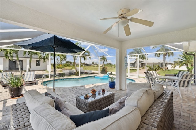 view of pool with glass enclosure, a patio, an outdoor living space, ceiling fan, and pool water feature